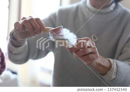 Woman untangling cotton with a brush Woman untangling cotton with a brush 137432340