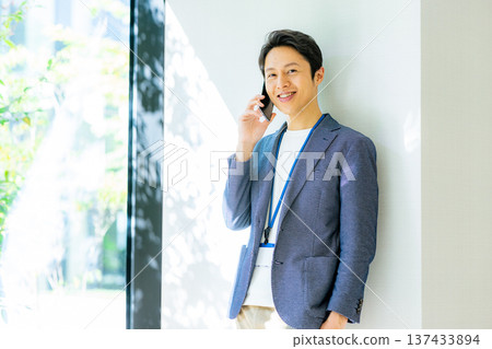 A man wearing a jacket and using a smartphone 137433894