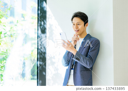 A man wearing a jacket and using a smartphone A man wearing a jacket and using a smartphone 137433895
