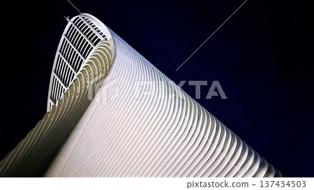 Modern minimalistic architecture reveals towering white shell as graceful vertical ribs rise upward toward curved arch, smooth surface and rhythmic lines sculpt bold silhouette against deep blue sky Modern minimalistic architecture reveals towering white shell as graceful vertical ribs rise upward toward curved arch, smooth surface and rhythmic lines sculpt bold silhouette against deep blue sky 137434503