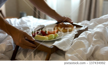 Breakfast tray with pastry and fresh fruit served on bed 137434992