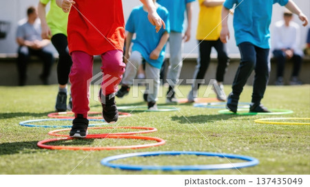 Children Running Through Agility Hoops on Grass 137435049