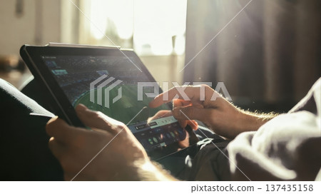 Watching soccer match on tablet in morning light Watching soccer match on tablet in morning light 137435158