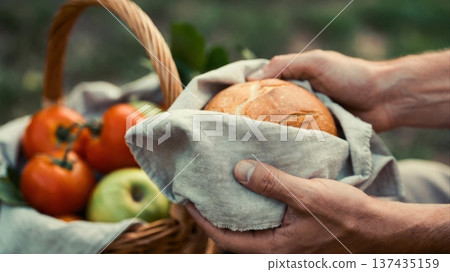 Holding fresh bread over basket of fruit outdoors Holding fresh bread over basket of fruit outdoors 137435159