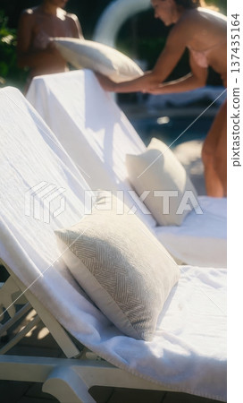 Poolside lounge chair with pillows being arranged 137435164