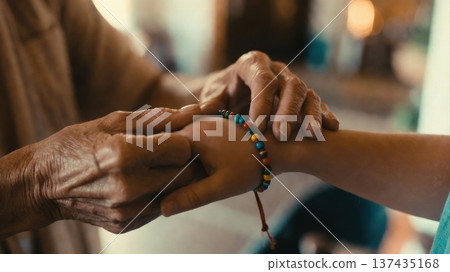 Elderly hands fastening colorful bracelet on child wrist Elderly hands fastening colorful bracelet on child wrist 137435168