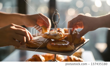 Hands reaching for pastries on tiered dessert stand 137435180