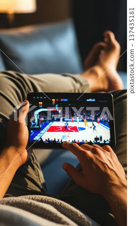 Watching basketball game on tablet while relaxing 137435181