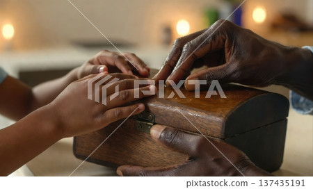 Adult and child opening wooden keepsake box together 137435191