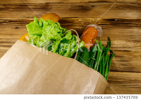 Paper bag with different food on wooden table. Grocery shopping concept 137435709