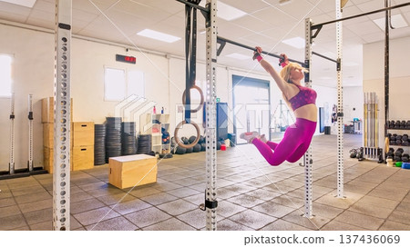 Athletic woman performing pull ups during strength training in gym Athletic woman performing pull ups during strength training in gym 137436069