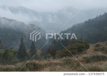 The mountain range in late autumn, shrouded in rain mist. Overlapping mountain ranges and a single bird. The mountain range in late autumn, shrouded in rain mist. Overlapping mountain ranges and a single bird. 137436075