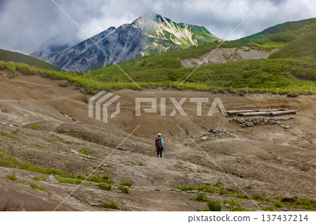 Climbers walking along the ridge of Mt. Yuori in the Northern Alps and Mt. Washu with clouds rising 137437214