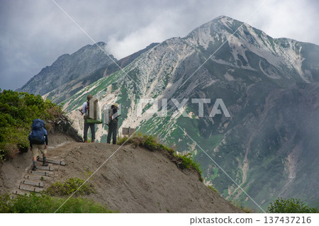 登山者們正沿著北阿爾卑斯山脈湯森山的山脊行走。遠處是鷲羽山和水翔山,雲霧繚繞。 登山者們正沿著北阿爾卑斯山脈湯森山的山脊行走。遠處是鷲羽山和水翔山,雲霧繚繞。 137437216