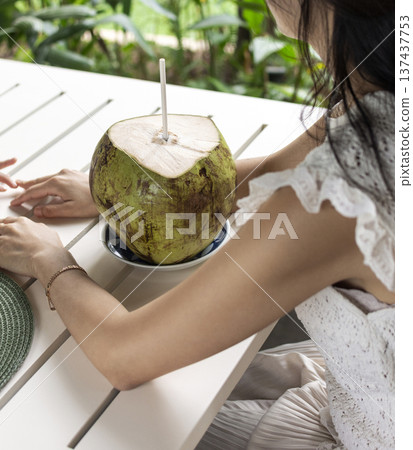 woman drinking fresh coconit in tropical outdoors garden cafe in bali indonesia woman drinking fresh coconit in tropical outdoors garden cafe in bali indonesia 137437753