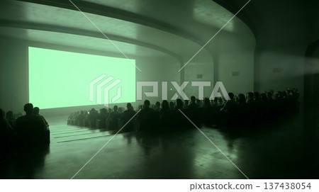 People sitting in a dimly lit movie theater, watching a large green screen projection, ready for content. 137438054