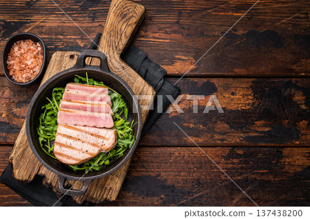 Tender grilled tuna steak on a bed of greens, an exquisite blend of flavors that delights the palate. wooden background. top view 137438200
