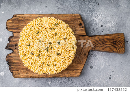 Twisted raw ramen noodles, ready to soak up flavors and bring warmth to your next culinary adventure. grey background. top view Twisted raw ramen noodles, ready to soak up flavors and bring warmth to your next culinary adventure. grey background. top view 137438232