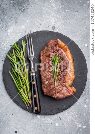 Close up of a flavorful grilled striploin or strip steak, garnished with herbs, ready to impress at your next dinner. grey background. top view 137438240