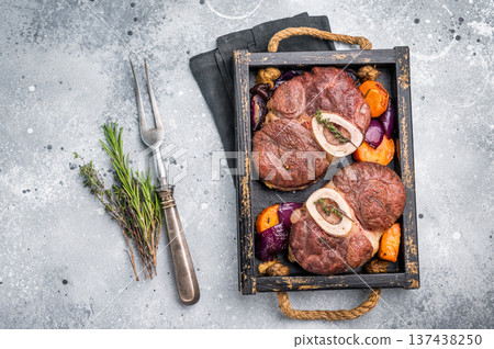 Flavorful ossobuco garnished with fresh herbs, osso buco shank ideal for impressing guests at your next dinner party. grey background. top view 137438250
