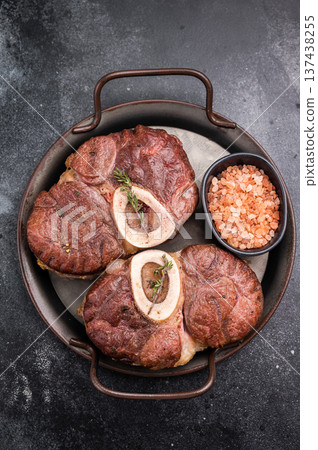 Deliciously braised ossobuco, featuring tender osso buco veal shank and rich marrow, perfect for a gourmet Italian feast. black background. top view Deliciously braised ossobuco, featuring tender osso buco veal shank and rich marrow, perfect for a gourmet Italian feast. black background. top view 137438255