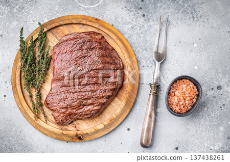 Perfectly grilled top sirloin steak, seared to a juicy finish and garnished with fresh herbs for an irresistible flavor. grey background. top view Perfectly grilled top sirloin steak, seared to a juicy finish and garnished with fresh herbs for an irresistible flavor. grey background. top view 137438261