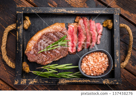 Deliciously charred grilled New York strip or striploin steak with rich marbling, an essential dish for any outdoor gathering. wooden background. top view Deliciously charred grilled New York strip or striploin steak with rich marbling, an essential dish for any outdoor gathering. wooden background. top view 137438276