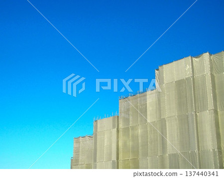公寓大樓建築工地上覆蓋著安全防護布，秋日的天空湛藍。 137440341