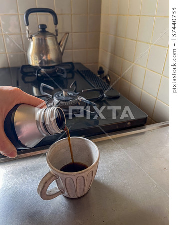 Hands of a person pouring canned coffee into a mug in the kitchen Hands of a person pouring canned coffee into a mug in the kitchen 137440733