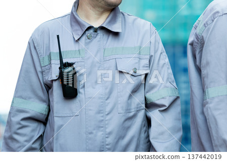Close up of industrial worker uniform with two way radio attached, safety communication equipment concept, construction site security and professional workforce detail Close up of industrial worker uniform with two way radio attached, safety communication equipment concept, construction site security and professional workforce detail 137442019