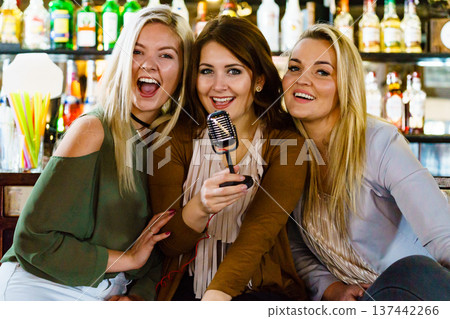 Women in bar singing karaoke Women in bar singing karaoke 137442266
