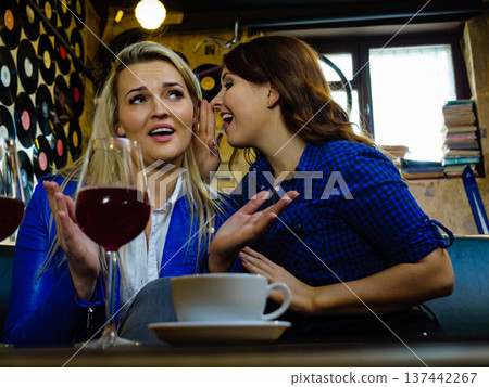 Two women gossiping in pub 137442267