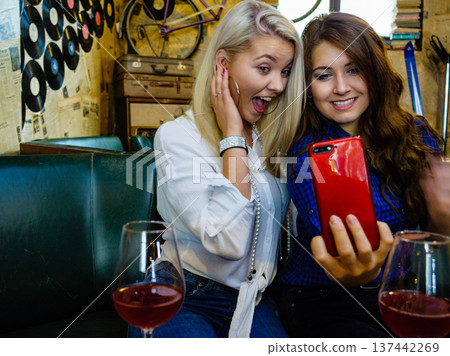 Girls in pub club taking self photo with phone 137442269