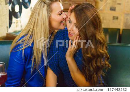 Two women gossiping in pub Two women gossiping in pub 137442282