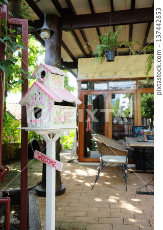 Cute sweet pink and white wooden Birdhouse with with welcome message on wood decorated outdoor of house 137442853