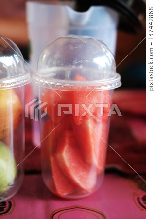Close up hand holding fresh watermelon pieces for smoothie in plastic glass of cafe in Thailand Close up hand holding fresh watermelon pieces for smoothie in plastic glass of cafe in Thailand 137442868