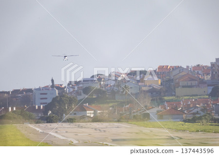 Small plane flying above urban houses 137443596