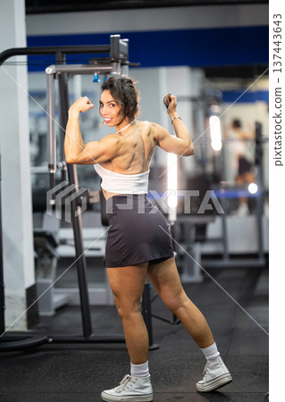 Strong woman flexing muscles showing back and bicep definition Strong woman flexing muscles showing back and bicep definition 137443643