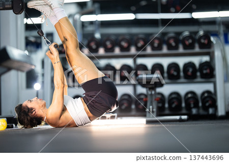 Woman exercising core muscles on cable machine in gym 137443696