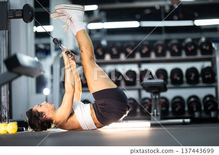 Woman training core muscles using cable machine in gym 137443699