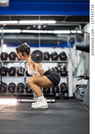 Woman doing barbell squats during gym workout Woman doing barbell squats during gym workout 137443716
