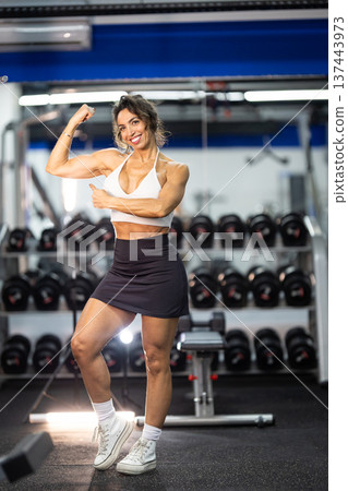 Confident woman flexing bicep showing gym fitness 137443973