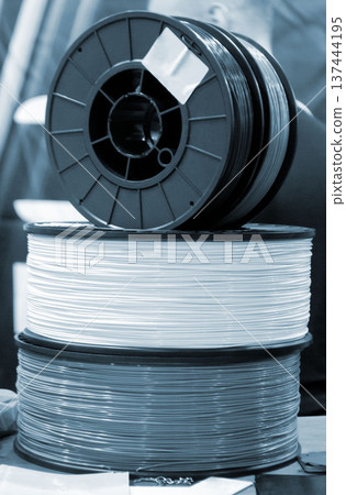 Spool of plastic wire for 3D printing. Spool with white plastic close-up. Component for 3d printing. Printing accessories. Concept modern 3D printing technology. Additive progressive FDM technologies Spool of plastic wire for 3D printing. Spool with white plastic close-up. Component for 3d printing. Printing accessories. Concept modern 3D printing technology. Additive progressive FDM technologies 137444195