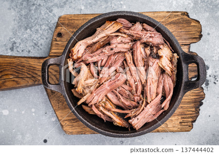 Savory pulled beef brisket served in a skillet, dipping creating an appealing and mouthwatering culinary scene. grey background. top view Savory pulled beef brisket served in a skillet, dipping creating an appealing and mouthwatering culinary scene. grey background. top view 137444402