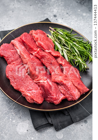Raw bison meat presented with fresh herbs and spices, inspiring bold flavors and unique recipes for adventurous food lovers. grey background. top view Raw bison meat presented with fresh herbs and spices, inspiring bold flavors and unique recipes for adventurous food lovers. grey background. top view 137444413