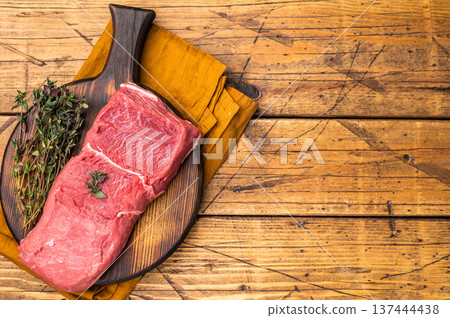 Fresh raw bison meat displayed on a wooden board, showcasing its rich red color and tenderness, ideal for gourmet cooking adventures. wooden background. top view Fresh raw bison meat displayed on a wooden board, showcasing its rich red color and tenderness, ideal for gourmet cooking adventures. wooden background. top view 137444438