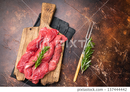Beautifully arranged raw horse meat slices on a wooden platter, showcasing its appealing color and texture, perfect for cooking inspiration. brown background. top view Beautifully arranged raw horse meat slices on a wooden platter, showcasing its appealing color and texture, perfect for cooking inspiration. brown background. top view 137444442