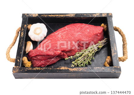 Raw beef topside on rustic wooden tray with thyme and garlic. Fresh lean inside round meat on isolated background with copy space. Raw beef topside on rustic wooden tray with thyme and garlic. Fresh lean inside round meat on isolated background with copy space. 137444470