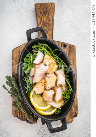 Pan fried white fish chunks on salad with lemon slices. Healthy seafood dish. 137444478