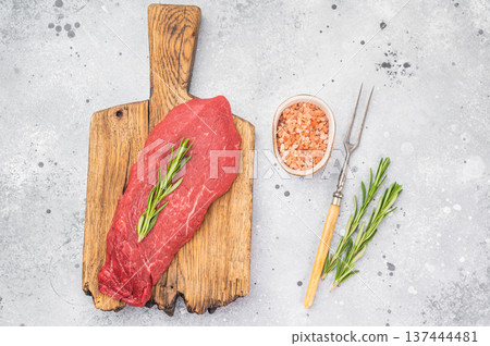 Raw beef inside round topside with herbs and seasoning on cutting board. Fresh lean red meat prepared for cooking on light rustic background. Raw beef inside round topside with herbs and seasoning on cutting board. Fresh lean red meat prepared for cooking on light rustic background. 137444481